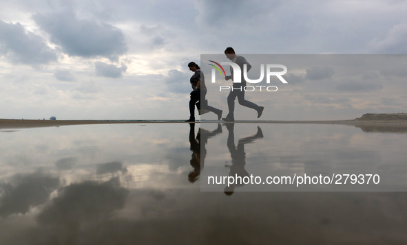 People walk past a flooded part of the Black sea coast line as they are reflected in the water after a heavy rain near the town of Varna, We...