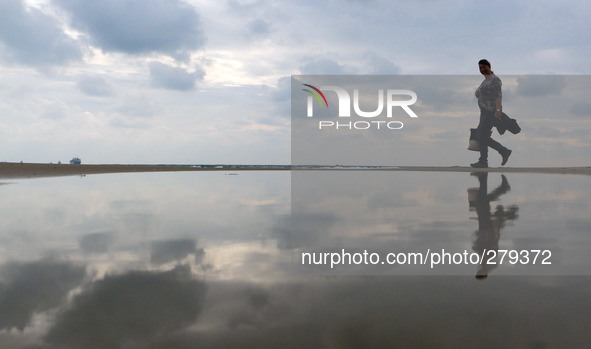 People walk past a flooded part of the Black sea coast line as they are reflected in the water after a heavy rain near the town of Varna, We...