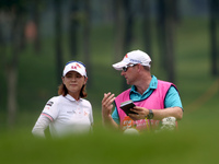 Na Yeon Choi of South Korea gets advice from her caddie before taking her second shot on the fairway of the eighteenth hole during the third...