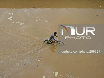 A Naga resident wade through flood water with his bicycle after heavy rain in Dimapur, India north eatern state of Nagaland on Sunday, Octob...
