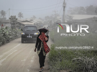 A woman with the traditional clothing covered the face in Payung village in Karo regency watches Mount Sinabung erupt in Indonesia's North S...