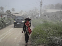 A woman with the traditional clothing covered the face in Payung village in Karo regency watches Mount Sinabung erupt in Indonesia's North S...