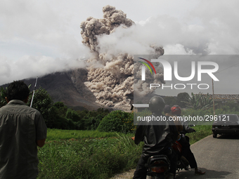 Residents watch from a distance Sinabung volcano with lava blowing a giant black cloud of volcanic ash after the eruption of the latest look...