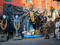  Police looks on unfinished idol of Kali, the Hindu goddess of destruction at Kumartuli or potters' zone i, India. Kali Puja, the festival d...