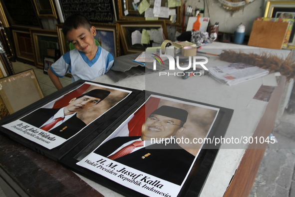 A child noticed a portrait of the President of Indonesia, Joko Widodo (L) and his deputy, Jusuf Kalla (R) is immediately displayed in a shop...