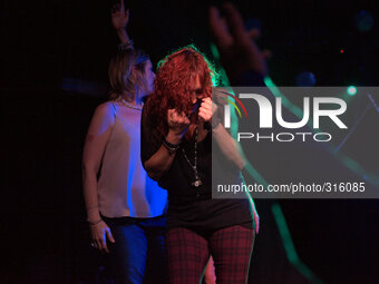 Green light shining through a member of the audience's hair as she and others are on stage. (