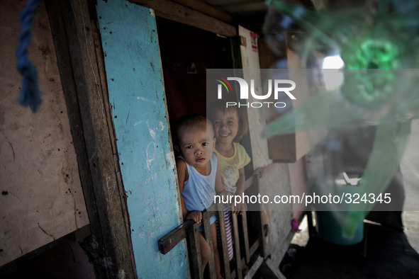 Children look from inside their home at a coastal village one year since Typhoon Haiyan hit in Tacloban, Leyte province, Philippines, Novemb...