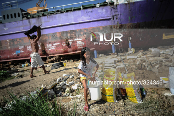 A girl passes by a ship that was washed ashore as she makes her way home after fetching water at a coastal village one year since Typhoon Ha...