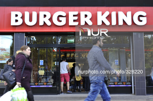 People walking in front of a branch of the restaurant chain, Burger King. 