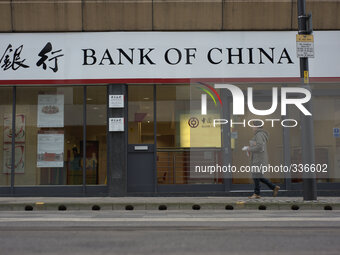 A woman walking along the street as she passes a branch of the Bank of China. (
