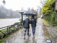 1st December Turin, Italy. Two people walking in a wet path parallel to the river Po, during a flooding alert after 48 h of continuous rain....