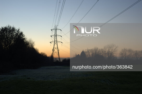 Electricity transmission lines silhouetted against the light of the setting sun on December 5, 2014 in Stockport, England, UK.
