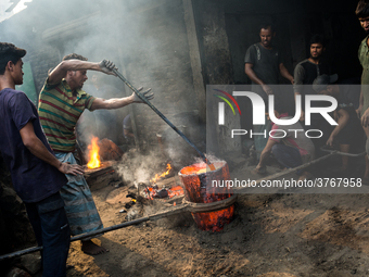 Workers work in a metal shop near shipyard where he breaks metal small pieces and puts them into the furnace. Dhaka, Bangladesh, February 7,...
