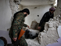 Two rebels carrying an explosive device through hole in wall, in Aleppo, Syria, on December 18, 2014. (