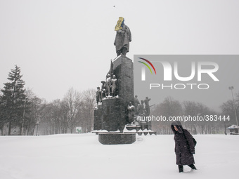 A woman wades through the snow on a background of the Shevchenko monument, in Kharkov, Ukraine, on December 30, 2014. (