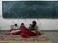 Palestinian family warm themselves inside the semester  at a United Nations (UN) run school sheltering Palestinians, whose houses were destr...