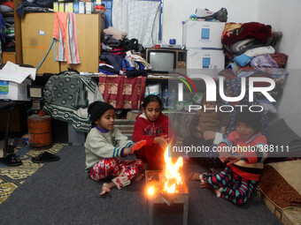 Palestinian family warm themselves on a fire on a winter  at a United Nations (UN) run school sheltering Palestinians, whose houses were des...