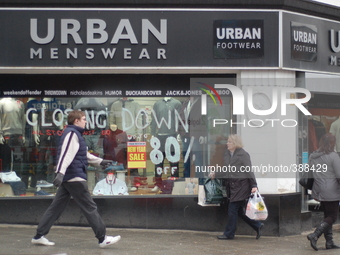 People walking by the Urban Menswear shop, in Stockport, which is in the process of closing down. (