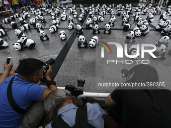 A group of photographers take photograph of a panda sculptures during the 1,600 Pandas World Tour at National Monument in Kuala Lumpur, Mala...