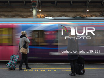 A train arriving at Preston station as two people wait on the platform. (