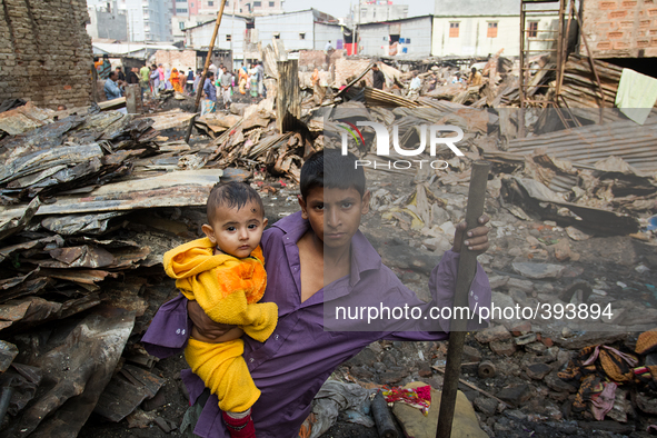 A boy with his brother in the lap was standing amid the remains of the gutted Poolpar Slum in Dhaka, Bangladesh while their mother was busy...