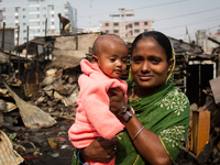 A mother with her child smiles happily amid the remains of the gutted Poolpar Slum in Dhaka, Bangladesh. (
