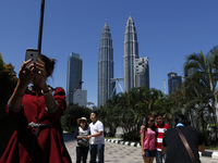 Tourists posing against the iconic Petronas Towers on January 14, 2015 in Kuala Lumpur, Malaysia. Malaysia aims to lure 29.4 millions touris...