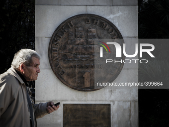 An old man walks in front of a monument of Drachma in Athens on December 22, 2014. (