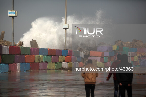 Palestinians walk on the seafront as a large wave collides with the break wall at the Gaza seaport in Gaza City on February 12, 2015 , durin...