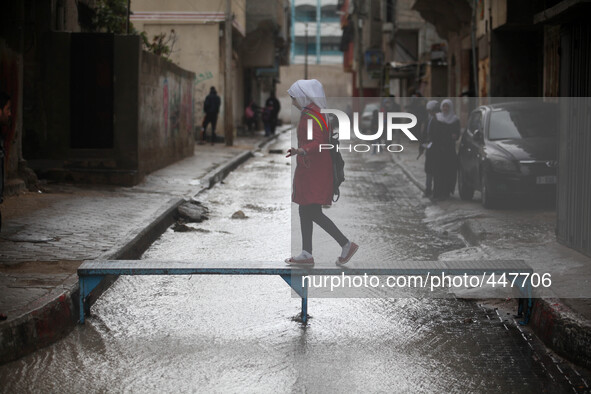 A Palestinian girl walk on a makeshift iron bridge over floodwaters in Shati refugee camp during a rain storm in Gaza City, Thursday, Feb. 1...