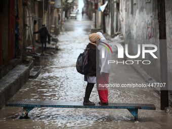 Palestinian girls walk on a makeshift iron bridge over floodwaters in Shati refugee camp during a rain storm in Gaza City, Thursday, Feb. 19...