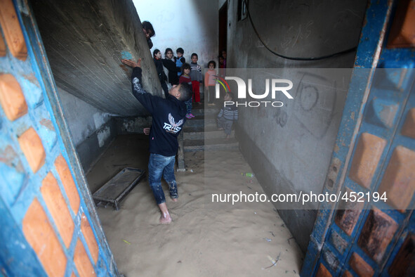 Palestinian children take out the rain water that flooded their home after heavy rains which flooded the Al Moghraka area in the central Gaz...