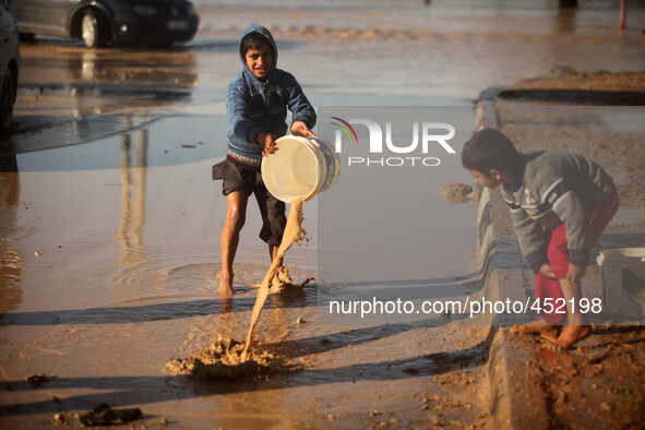 Palestinian children take out the rain water that flooded their home after heavy rains which flooded the Al Moghraka area in the central Gaz...