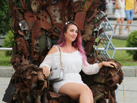 A woman poses for a picture sitting on iron Throne installed at Independence Square in Kyiv,  Ukraine, June 28, 2019. 