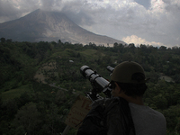Residents of Mount Sinabung monitor activity using binoculars mount monitors in Karo, Sumatra Island, Indonesia on March 1, 2015. The villag...