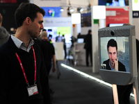 A worker from Awabot, speaking with his friend, with the Awabot Robot, during the first day of Mobile World Congress 2015 in Barcelona, on M...