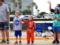  Aidan Rennert (center) wears a space suit while he and his older brother Judah watch a parade which included 13 astronauts riding in vintag...