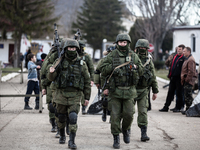 Alleged Russian soldiers in full body armor and armed with an assault rifles are marching away from the besieged Ukrainian Military Base in...