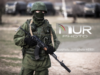 An alleged Russian soldier in full body armor and armed with an assault rifle standing in front of the besieged Ukrainian Military Base in P...