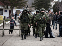 Alleged Russian soldiers in full body armor and armed with an assault rifles are marching away from the besieged Ukrainian Military Base in...