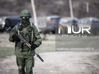 An alleged Russian soldier in full body armor and armed with an assault rifle standing in front of the besieged Ukrainian Military Base in P...