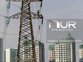 Operators work on a high voltage tower in Jakarta, Indonesia, July 27, 2019.  (