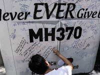 A man writes a message on a board for the missing Malaysian Airlines MH370 during the Day of Remembrance for MH370 in Kuala Lumpur, Malaysia...