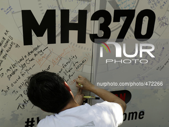 A man writes a message on a board for the missing Malaysian Airlines MH370 during the Day of Remembrance for MH370 in Kuala Lumpur, Malaysia...