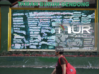 A women passing through the Taman Buruh Gendong (Freight Workers park) which the names of the workers written on the wall as a form of appre...
