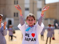 Palestinian school children fly kites to show solidarity with the Japanese people, near the Japan-funded housing project in Khan Younis in t...