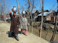 SRINAGAR, KASHMIR, INDIA - MARCH 21: Kashmiri women carry metal pitchers filled with drinking water  on the World Water Day on March 22, 201...