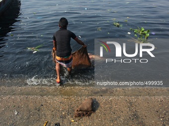A man is washing a sack used for carrying vegetable at the bank of river Buriganga, Dhaka, Bangladesh, 24 March, 2015. (
