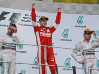 Malaysian Formula One Grand Prix winner, German Sebastian Vettel (C) of Scuderia Ferrari, second placed, British Lewis Hamilton (L) of  Merc...