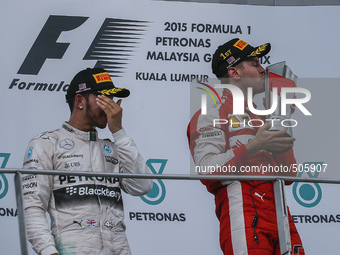 Winner of Malaysian Formula One Grand Prix, German Sebastian Vettel (R) of Scuderia Ferrari kisses the trophy as second placed, British Lewi...